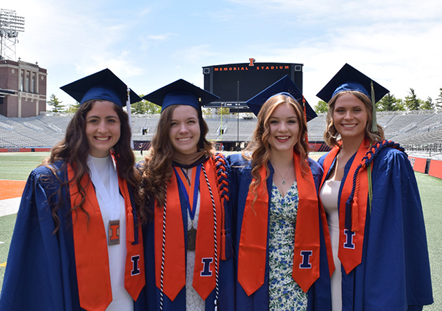 Megan and her friends in cap and gown at Commencement in Memorial Stadium
