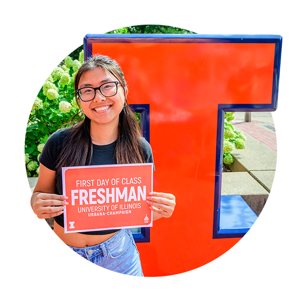 student posing with Block I holding up a sign that reads First Day of Class