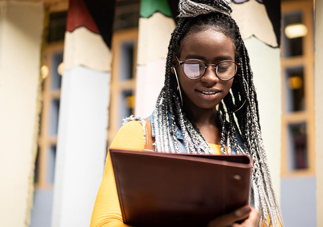 confident and smiling student holding their books