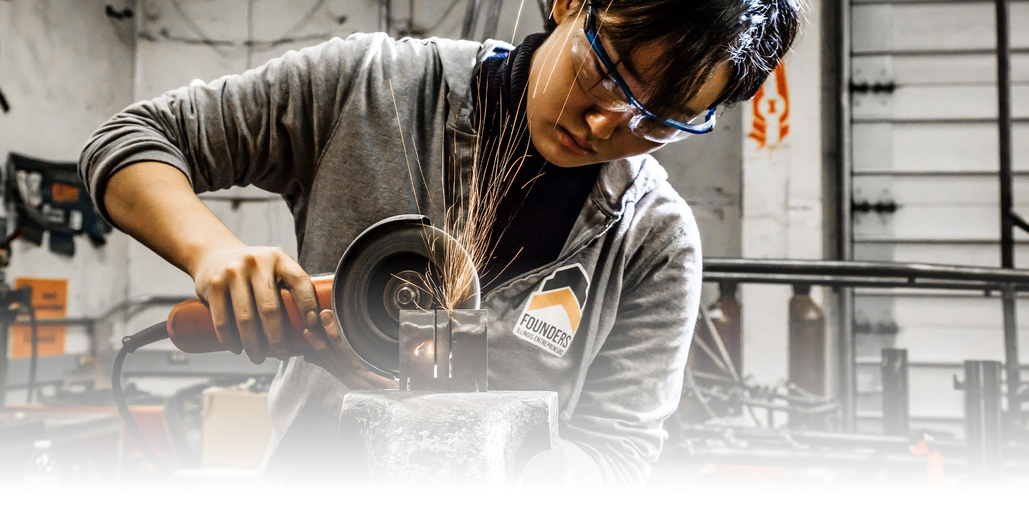 A female student uses a grinder at the Engineering Student Project Lab in the College of Engineering