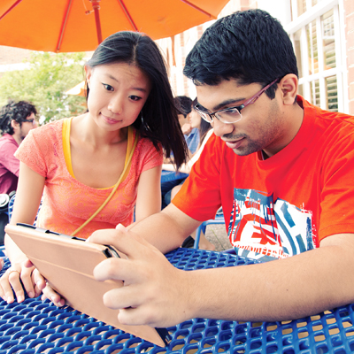 a male and female student reviewing an assignment on an tablet