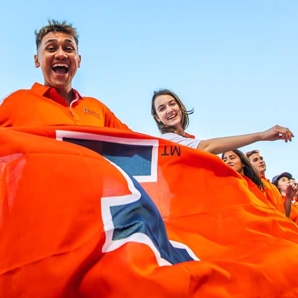 excited students holding large, orange Block I flag at Sights and Sounds, a new student event