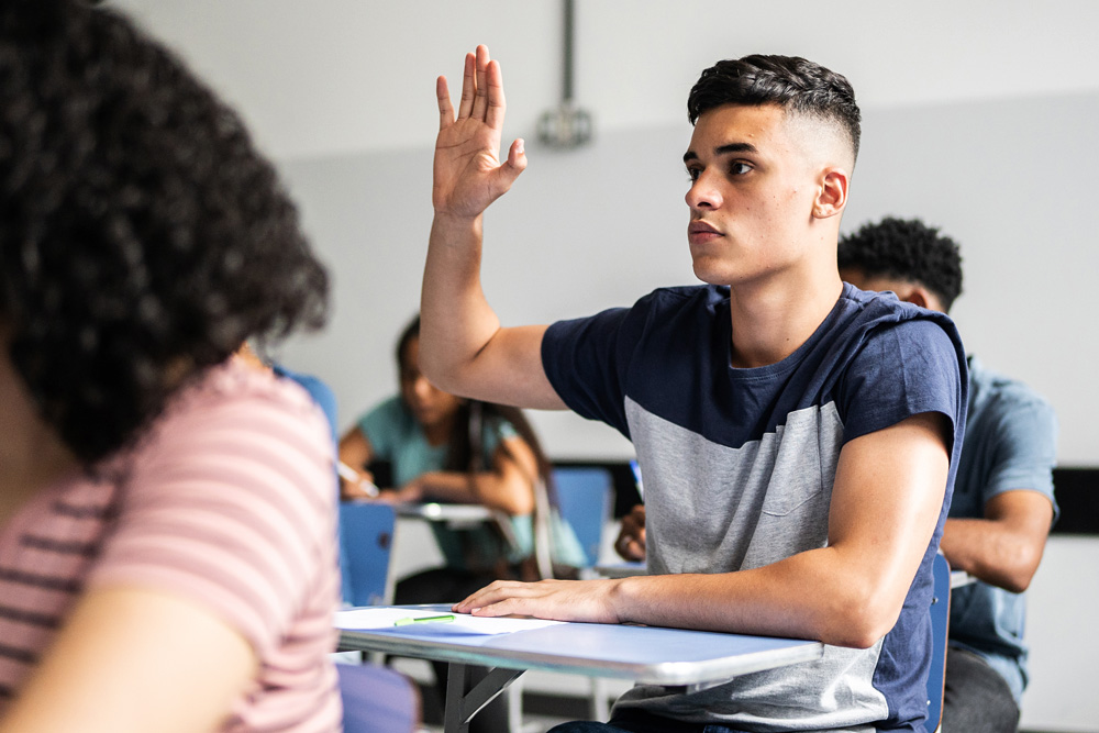 high school student raises hand during class