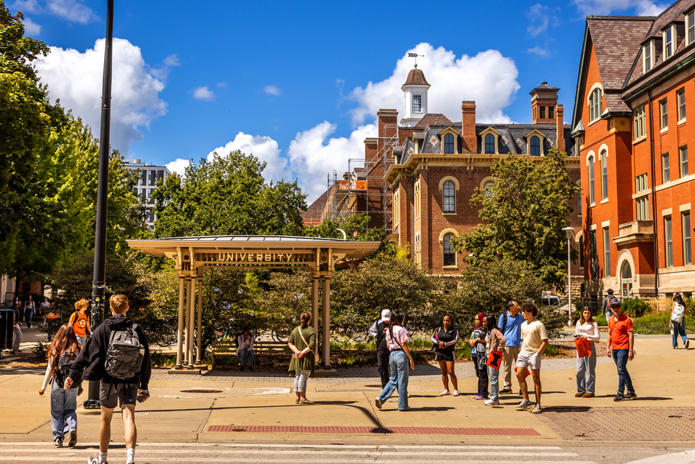 Admissions campus tour group stopped along Mathews Ave and the Natural History Building, Illini Union in the background