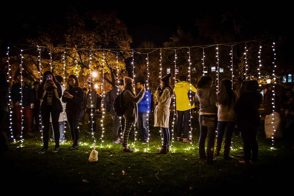 students interact with an installation of lights during Diwali Festival of Lights on the Quad at night