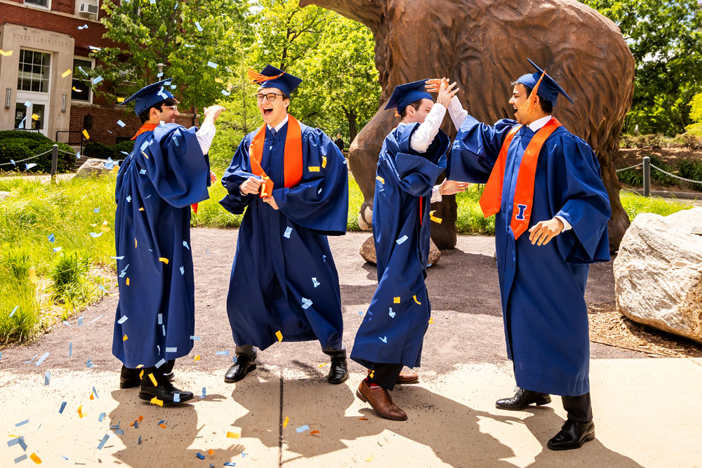 group of graduates throwing confetti in front of the Woolly Mammoth outside the Natural History Building