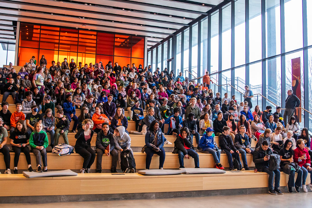 high school students attending a campus event wait patiently on the steps inside the Campus Instructional Facility