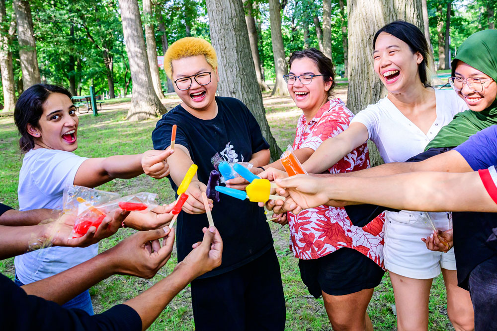 students huddle together with their popsicle treats at a summer fun afternoon picnic sponsored by International Education and ISSS