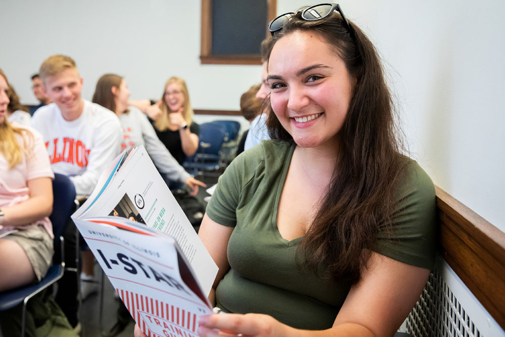 newly hired ISTARs attending on campus training session, one holds a training guide