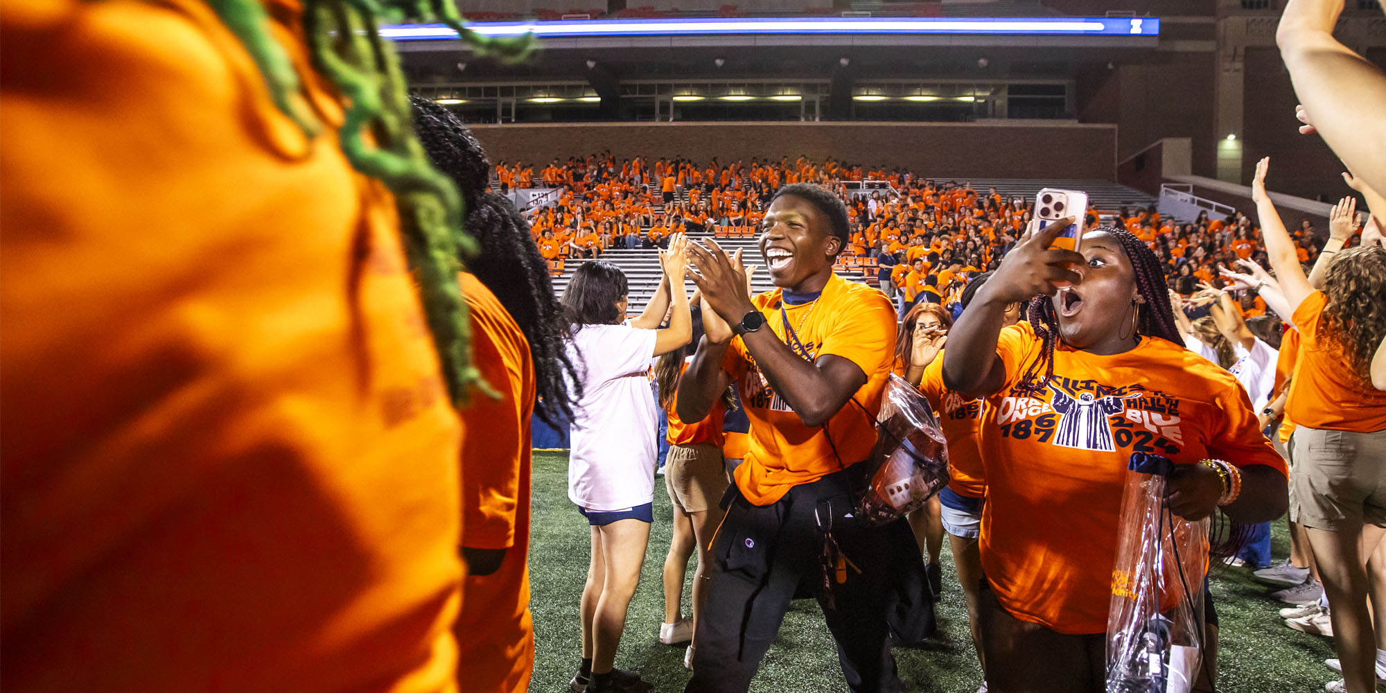excited incoming students empty the bleachers at Memorial Stadium and make their way onto the field during Sights and Sounds, a welcome week event
