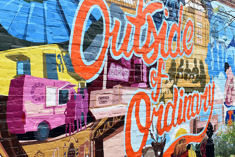 colorful mural painted in downtown Champaign depicting favorite spots around the Champaign-Urbana area and the phrase "Outside of Ordinary"