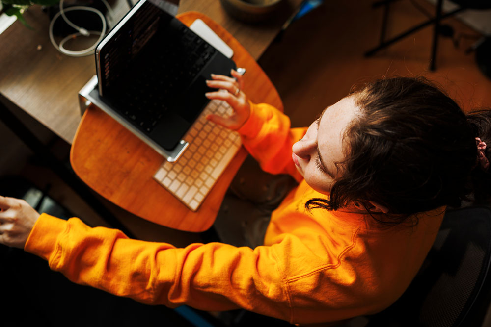 student in orange logging in to a video call on their laptop