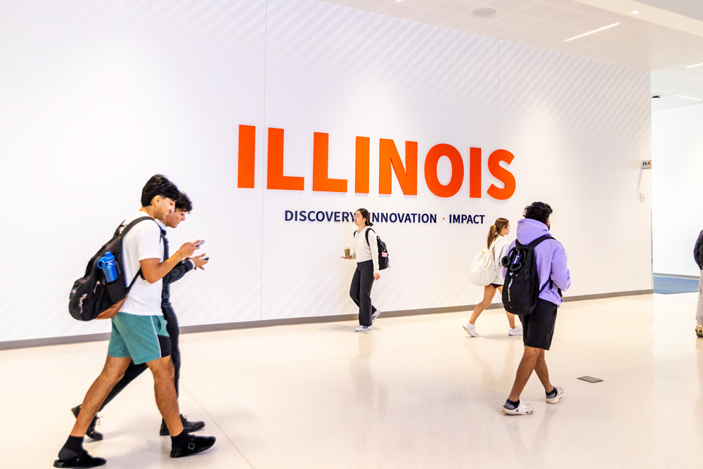students walking through Wymer Hall and large Illinois display on wall