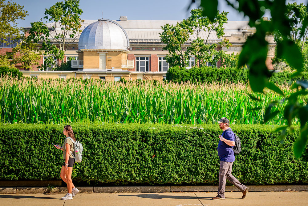 students alongside the Morrow Plots containing corn nearly ready to harvest, the campus Observatory stands in the background